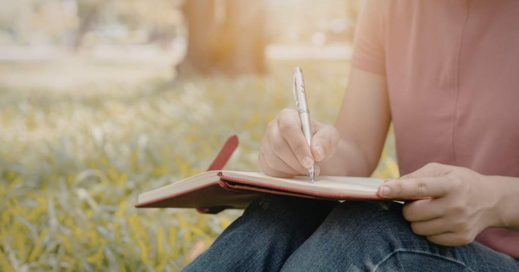 Person writing in a notebook outdoors, representing how an accountability system helps turn effort into steady progress
